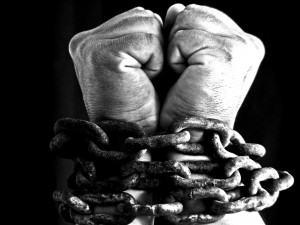 man's hands bound in chains