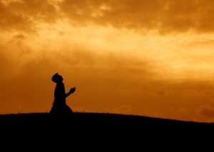 silhouette of a man kneeling in prayer
